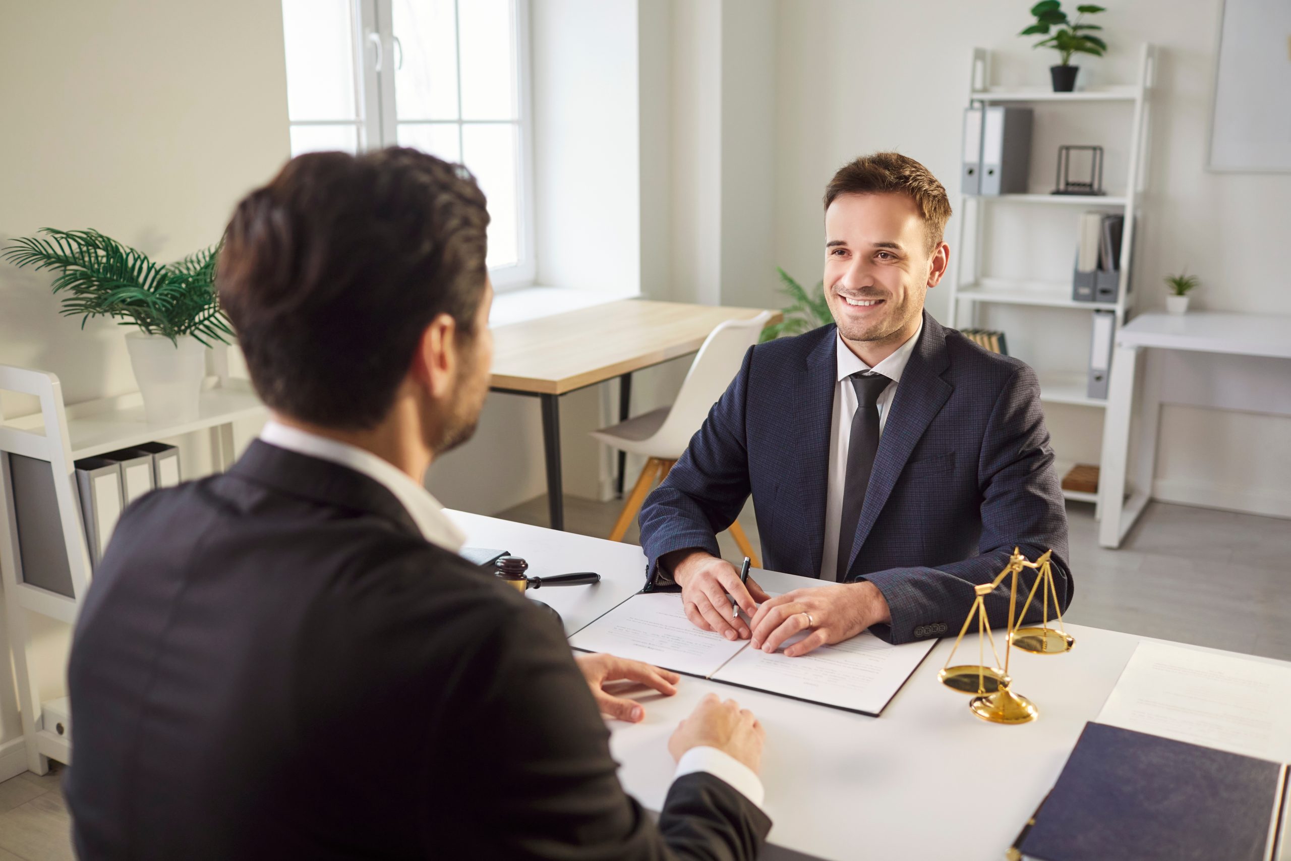 Smiling,Male,Lawyer,In,Suit,Sitting,At,Desk,With,Legal